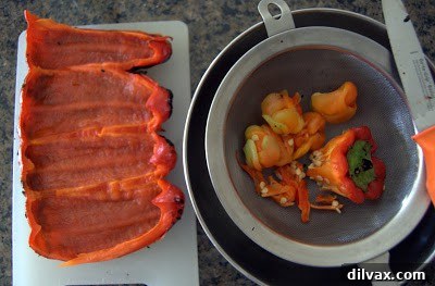 Roasted red pepper, sliced open and flattened, with seeds being removed.