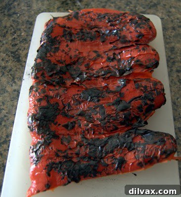 Carefully scraping the charred skin off a roasted red pepper with a knife.