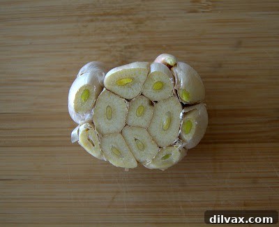 Carefully cutting the top off a head of garlic to expose the cloves before roasting.