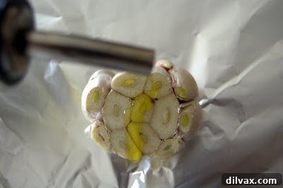 Drizzling olive oil over the exposed cloves of a garlic head for roasting.