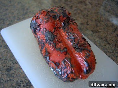 A red bell pepper perfectly charred and blistered from roasting, ready for the next step.