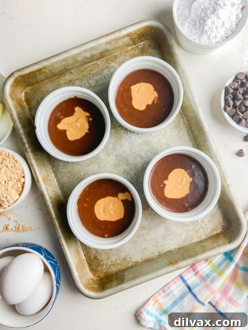 Ultimate Peanut Butter Chocolate Molten Cakes 6 Chocolate Lava cake batter with a dollop of peanut butter filling centered in four ramekins, ready for baking.