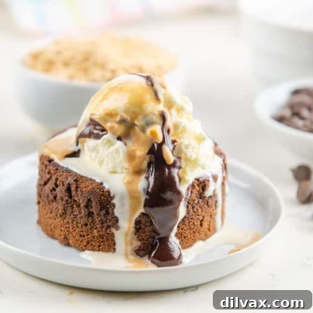 Peanut Butter Chocolate Lava Cake topped with ice cream and peanut butter and chocolate drizzle, revealing its molten center.