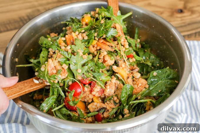 Tossing a Couscous Salad with Chicken in a large bowl, showcasing fresh ingredients.