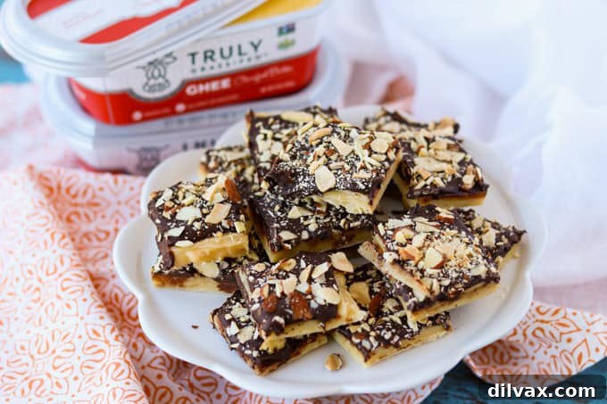 Silken Milk Toffee 2 A plate full of golden-brown chewy toffee pieces, some covered in chocolate and chopped almonds.