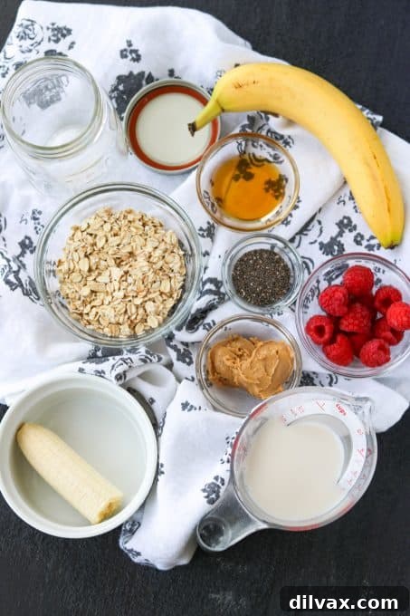 Various ingredients laid out to make overnight oats, including almond milk, rolled oats, almond butter, maple syrup, flax seeds, and bananas.