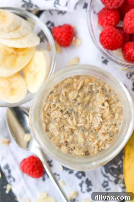 A close-up shot of creamy Banana Overnight Oats in a mason jar, topped with fresh fruit and nuts.