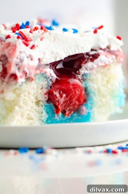 A perfectly sliced piece of red, white, and blue Patriotic Poke Cake, showcasing its vibrant layers and inviting texture.