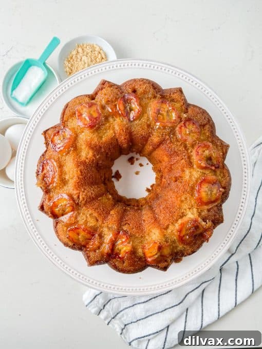 A whole Peanut Butter Upside Down Banana Cake on a white platter, garnished with fresh whipped cream.