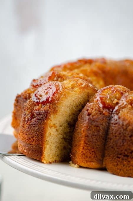 A slice of Peanut Butter Banana Cake on a cake plate, with the rest of the cake in the background.