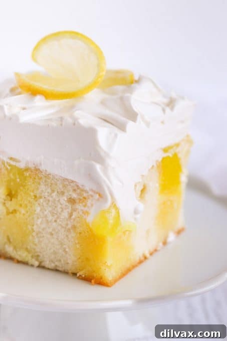 A vibrant Lemon Poke Cake with layers of lemon gelatin, lemon pie filling, and fluffy marshmallow frosting, showcasing its irresistible appeal.