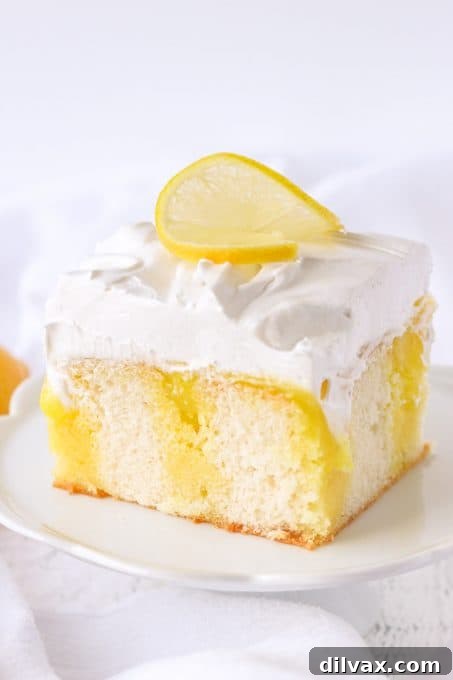 A slice of Lemon Marshmallow Poke Cake with a side view of its layers.