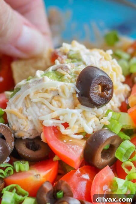 Overhead shot of 7-Layer Dip with a perfect scoop missing, showcasing its delicious layers.