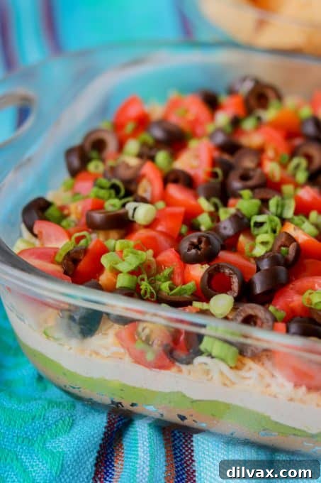 Close-up of a chip scooping up a generous portion of the 7-Layer Dip, highlighting the distinct layers.