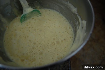 The first layer of genoise cake being moistened before adding cream.