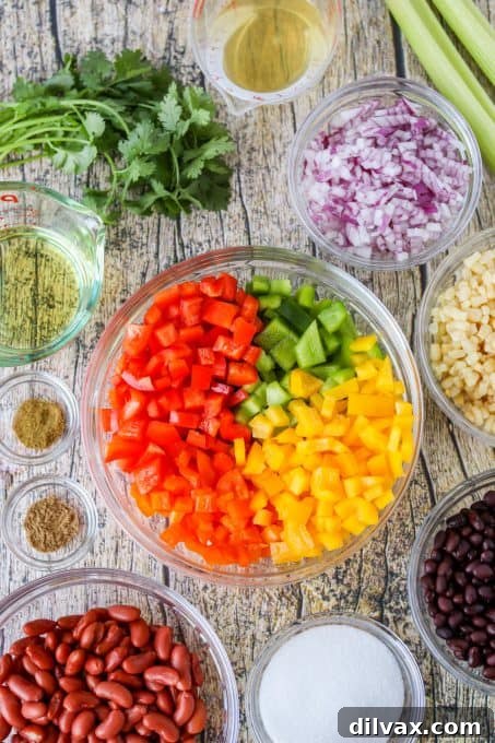 A collection of fresh ingredients ready for making Texas Caviar, including bell peppers, red onion, celery, beans, and corn.