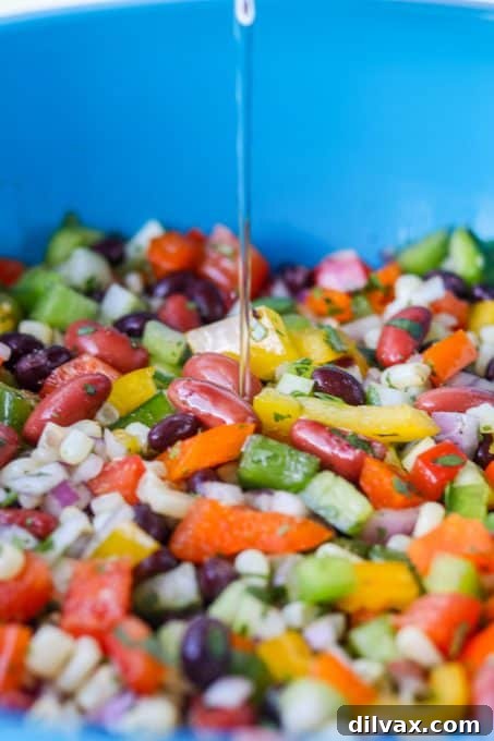 The process of pouring the zesty marinade over the colorful mixture of ingredients for Texas Caviar in a large bowl.