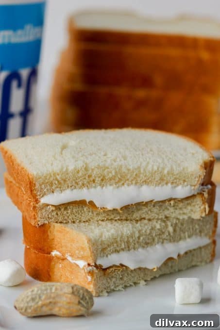 Effortless Fluffernutter Bliss 6 A completed Fluffernutter sandwich, expertly sliced diagonally and resting on a white plate, inviting a bite.