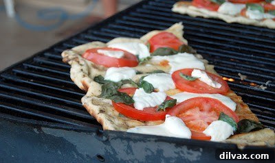 Freshly baked grilled Margherita pizza on a cutting board, ready to be served.