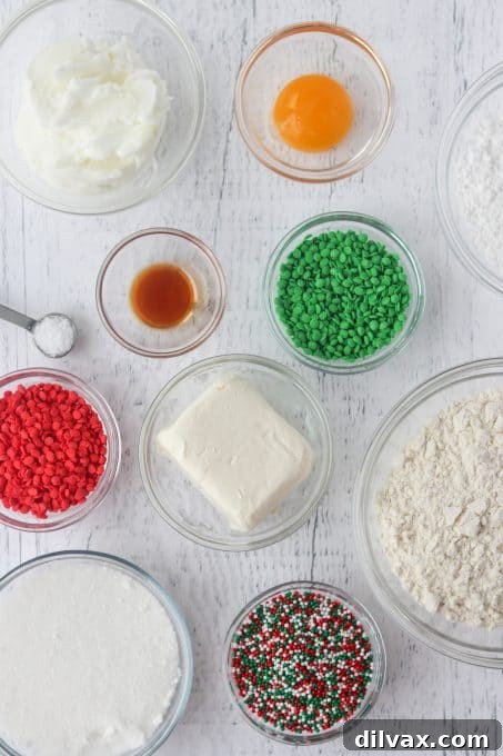 A collection of ingredients laid out for making cream cheese cookies with sprinkles.