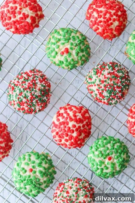 Freshly baked Christmas cookies coated in colorful sprinkles on a cooling rack.