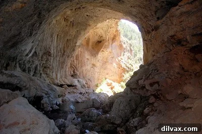 A wider perspective of the natural arch and surrounding canyon.