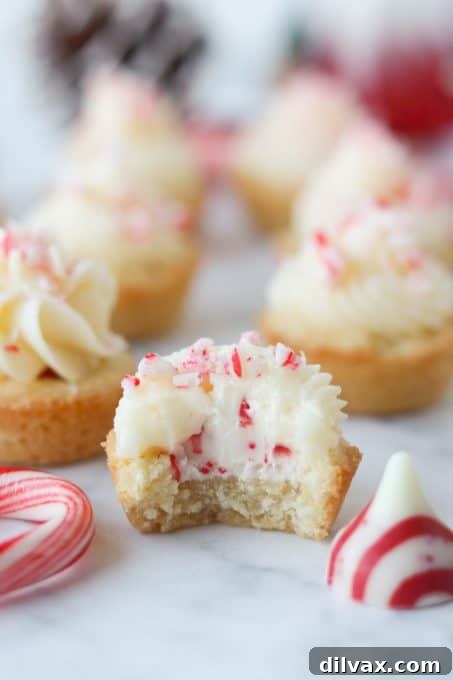 Mini Peppermint Cookie Cups 7 A bite taken out of a cookie cup with a candy cane Hershey's kiss inside.