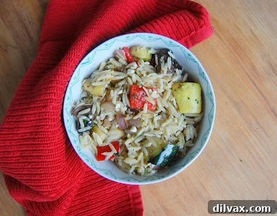 A close-up, appetizing view of the finished Grilled Vegetable, Feta and Orzo Salad in a rustic serving bowl, showcasing its vibrant colors, varied textures, and fresh herbs, ready to be enjoyed.