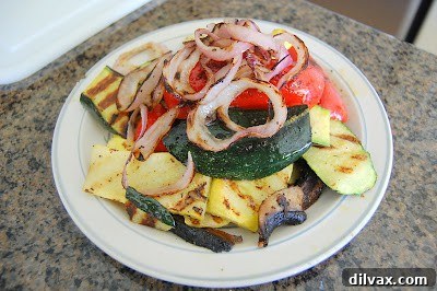 A selection of freshly grilled vegetables, including zucchini, squash, and bell peppers, neatly arranged on a clean white plate, allowed to cool gently after being removed from the heat.