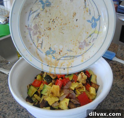 An overhead view of colorful, bite-sized grilled vegetables being added to a large bowl filled with cooked and cooled orzo pasta, ready for combining.