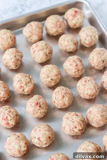 Unbaked sausage and cheese balls neatly arranged on a baking sheet, ready for the oven or freezer.