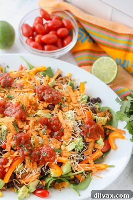 A close-up shot of a fork digging into a fully assembled chicken taco salad, highlighting the layers of ingredients.