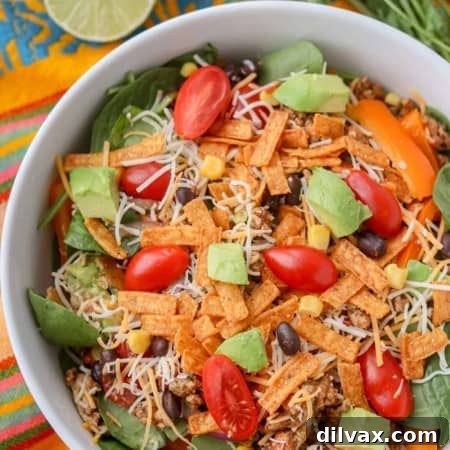 A bowl of salad with taco seasoned chicken, spinach, black beans, corn, and more.