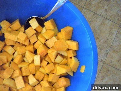 Butternut squash cubes seasoned and spread on a baking sheet.