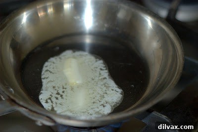 Fresh sage leaves frying in butter in a skillet.