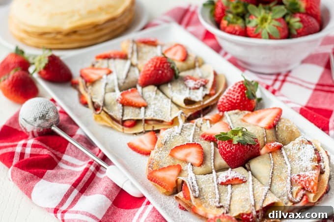 Decadent Strawberry Nutella Crepes 2 A plate full of crepes filled with strawberries and Nutella.