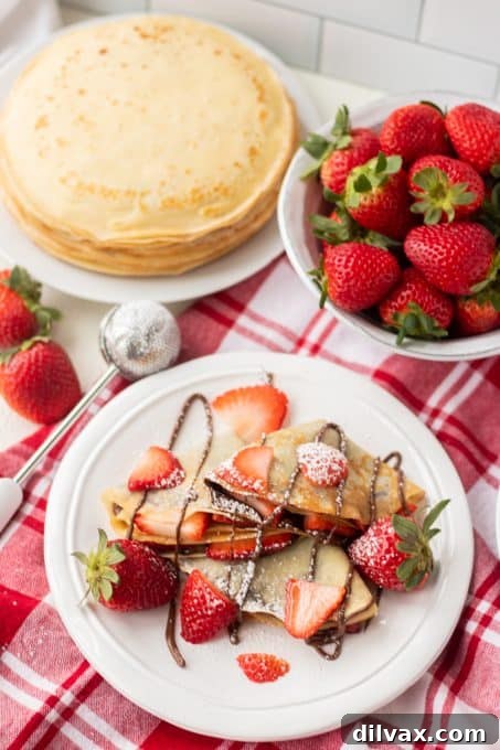 Decadent Strawberry Nutella Crepes 7 A plate full of crepes filled with strawberries and Nutella.