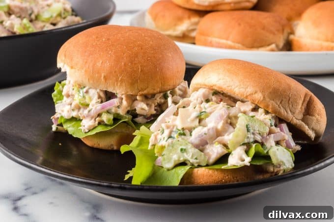 Sandwiches made with chicken and buttermilk. A close-up shot of a chicken salad sandwich with fresh green garnish, served on a rustic wooden board.
