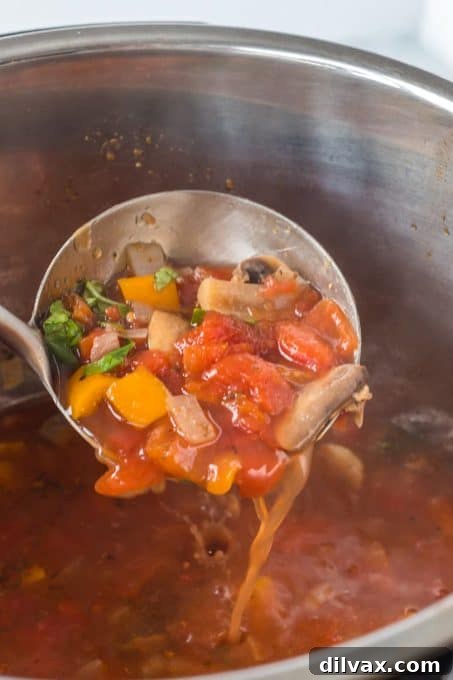 A vibrant bowl of Pizza Soup with a side of fresh breadsticks and a small green salad.