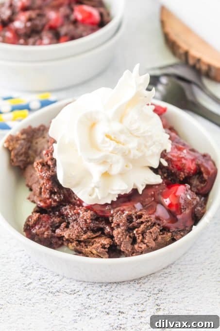 Effortless Chocolate Cherry Delight 8 A scoop of whipped cream atop a serving of the cake, with cherry pie filling visible.