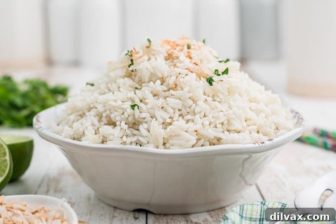 Fragrant Coconut Rice 2 A beautifully presented bowl of fluffy coconut rice, garnished with fresh herbs and lime wedges.