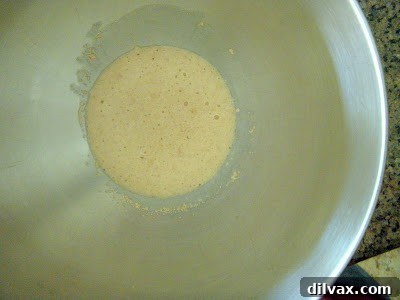 Active dry yeast blooming in warm water with sugar, forming a foamy layer.