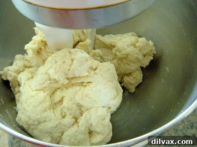 Smooth, elastic dough being kneaded thoroughly by a dough hook in a stand mixer, indicating proper gluten development.