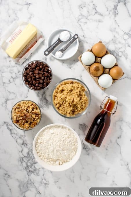 Various ingredients for chocolate chip blondies laid out on a kitchen counter: butter, brown sugar, eggs, vanilla, flour, salt, baking powder, chocolate chips, and walnuts.