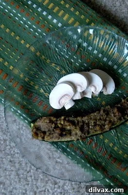 Savory Mushroom Onion Zucchini Boats 11 End shot of a single Mushroom and Onion Stuffed Zucchini boat on a white plate, garnished with fresh herbs.