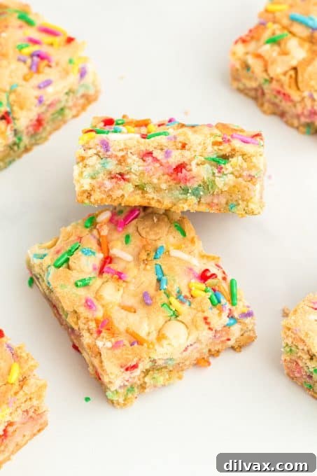 A close-up of a stack of Funfetti Ooey Gooey Bars on a cooling rack, showcasing the layers and colorful sprinkles.