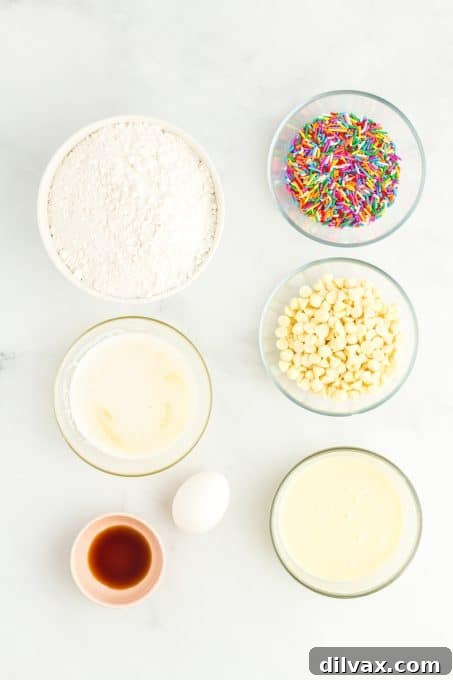 Essential ingredients for Funfetti Ooey Gooey Bars laid out on a surface, including cake mix, butter, egg, vanilla, white chocolate chips, sprinkles, and sweetened condensed milk.