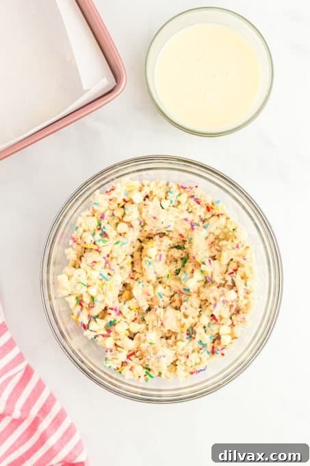Close-up of dough with white chocolate chips and colorful jimmie sprinkles being folded in before baking.