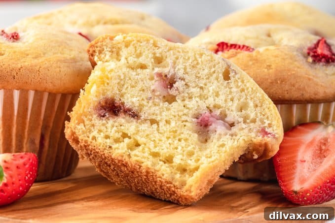 The inside of a strawberry muffin, showcasing its tender crumb and pieces of fresh strawberries.
