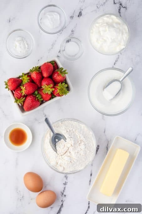 A selection of fresh ingredients including flour, sugar, eggs, butter, sour cream, and strawberries, laid out for baking.